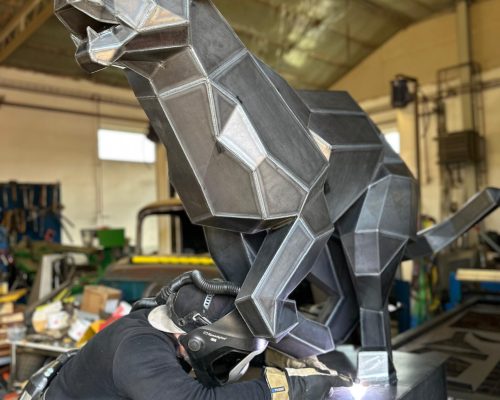 svetsar skulptur i verkstad